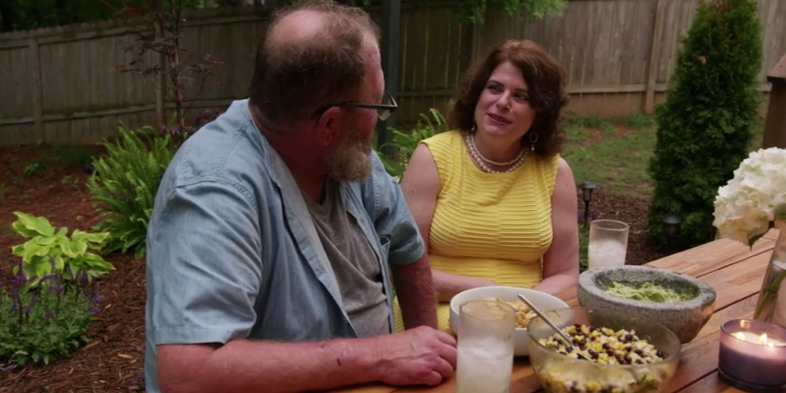 Tom and Abby sit at a picnic table, smiling at each other