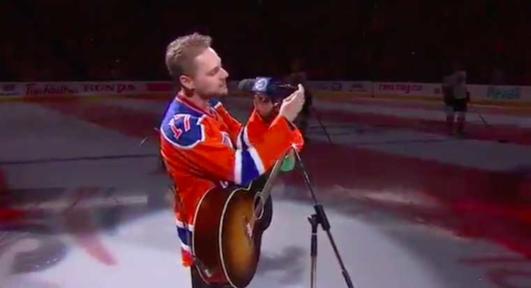 hockey fans sing national anthem: singer's broken microphone shown
