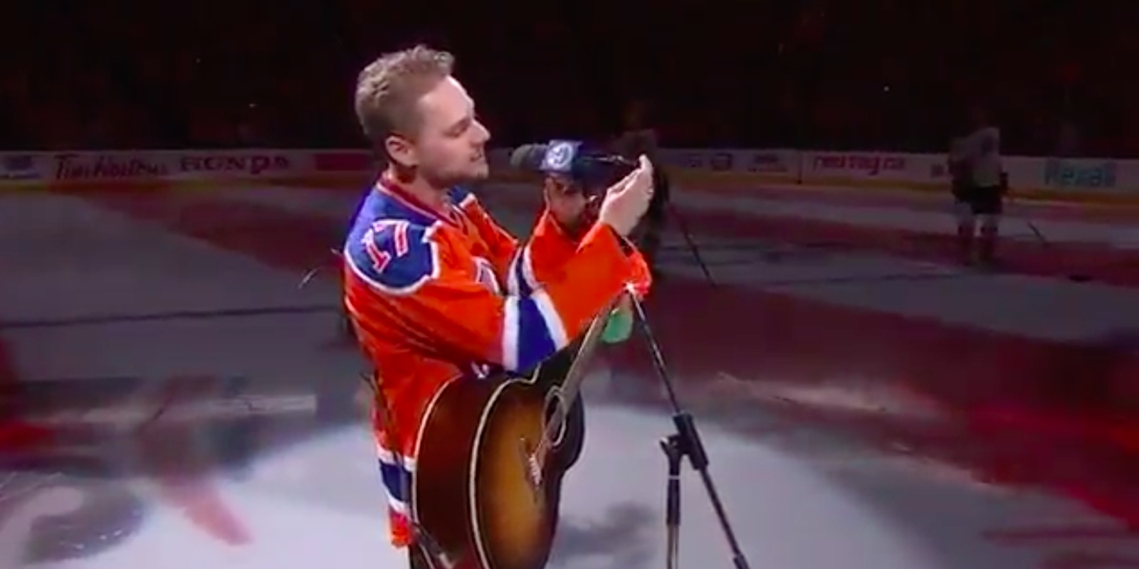 hockey fans sing national anthem: singer's broken microphone shown