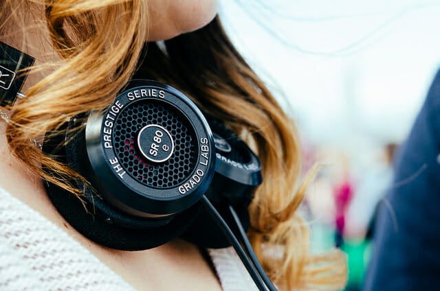 A young woman wears headphones around her neck.