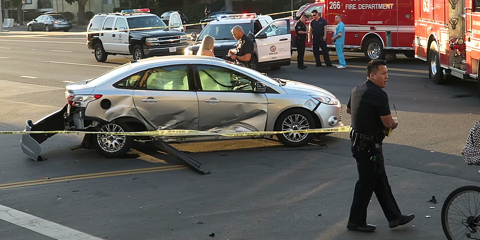 Police officer deploying yellow tape around accident scene