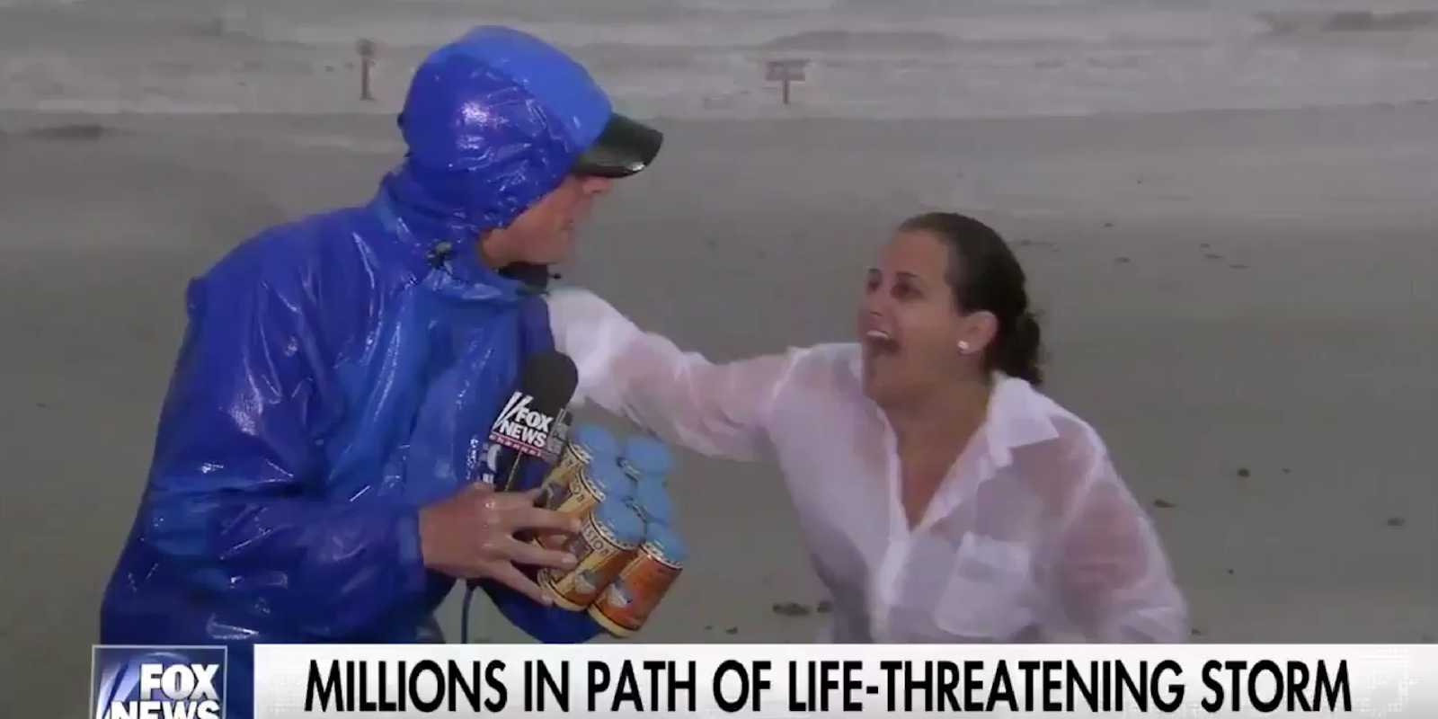 A woman interrupts live national Hurricane Harvey coverage to hand the reporter a six-pack of local Galveston, Texas beer.
