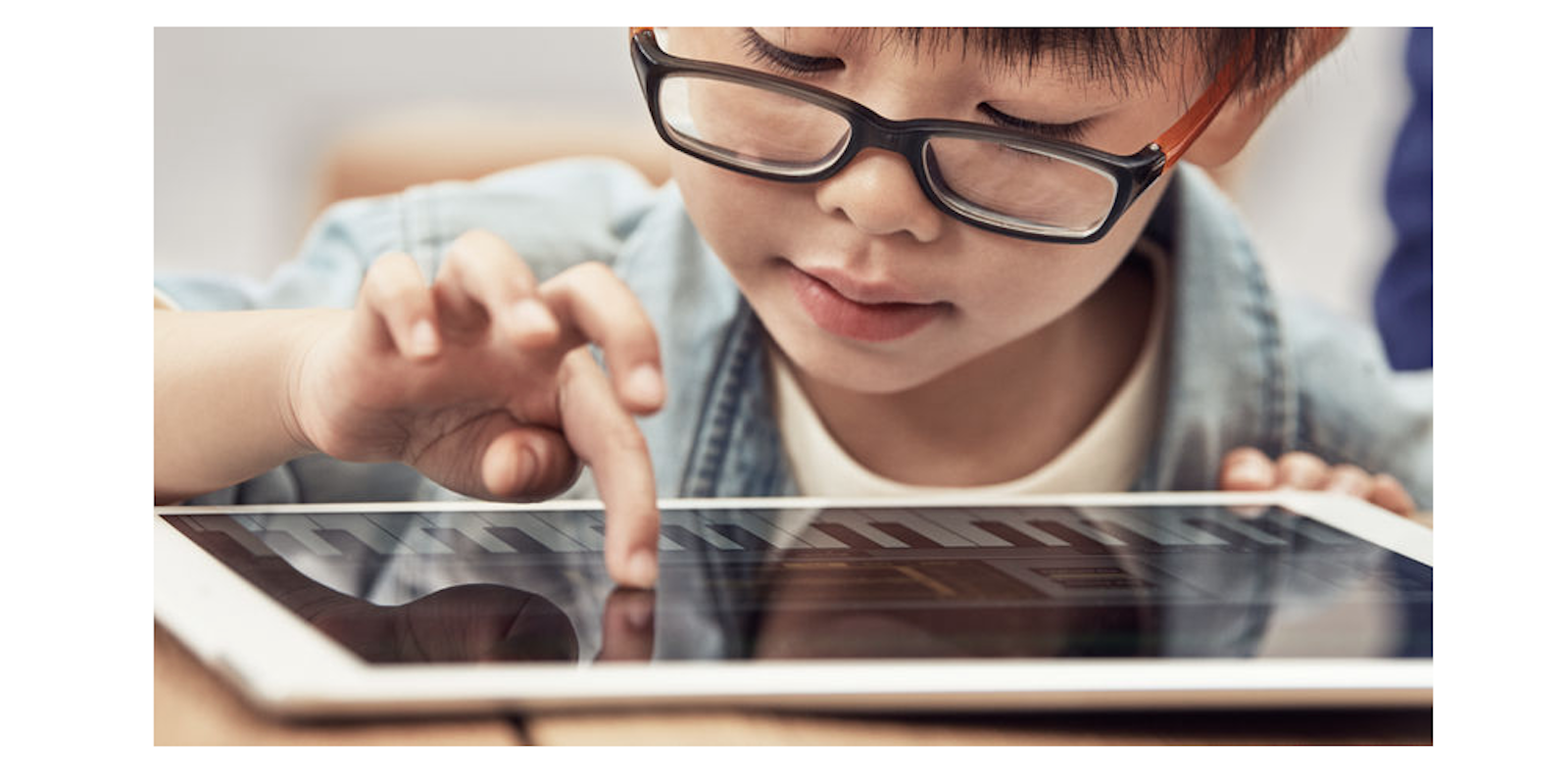 Child wearing glasses using iPad