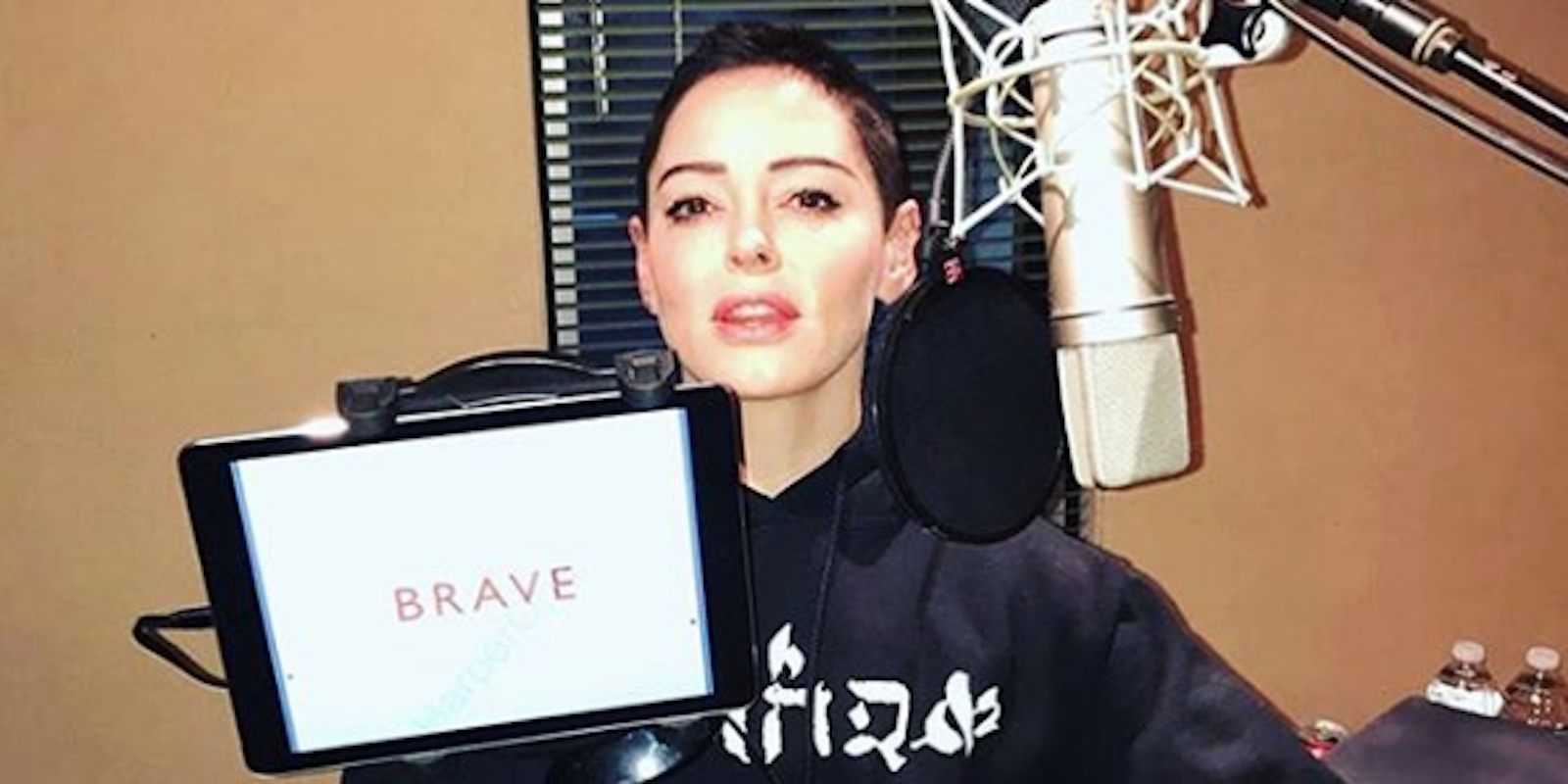 Rose McGowan holds up an iPad displaying the title of her book, 'Brave'